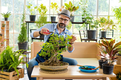 Portrait of young man holding potted plant