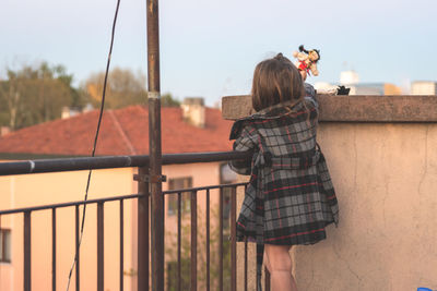 Rear view of girl playing with dolls on building terrace