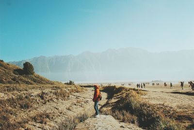 Rear view of man standing on mountain against clear sky
