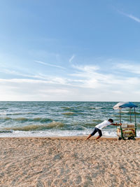 Side view of man on beach against sky