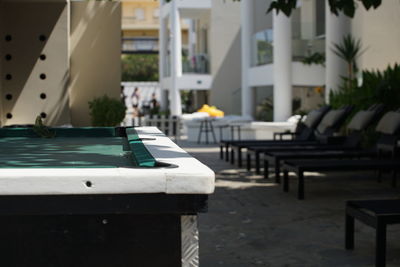 Empty chairs and tables in swimming pool against building