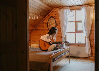 Woman playing on the guitar in country house