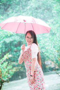 Portrait of woman with umbrella standing in rain