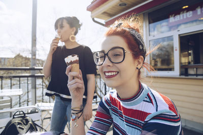 Hipster female friends eating ice cream by shop