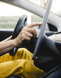 Woman using digital tablet while driving electric car