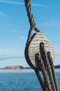 Close-up of rope tied on wood against sky