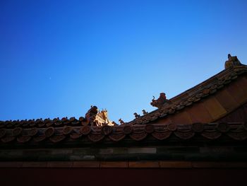 Low angle view of sculpture on roof against sky