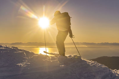 Low angle view of man standing on mountain against sky during sunset