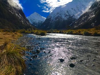 Scenic view of lake by snowcapped mountains against sky