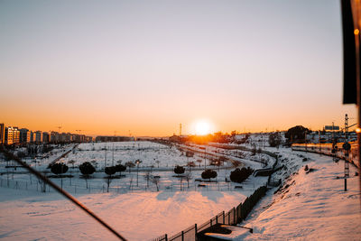 Scenic view of snow covered buildings against sky during sunset