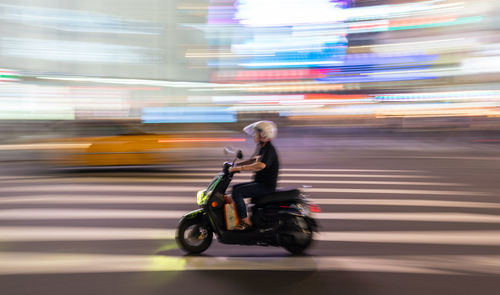 Blurred motion of woman riding motorcycle on road