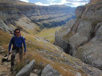 High angle portrait of male hiker standing against valley at ordesa y monte perdido national park