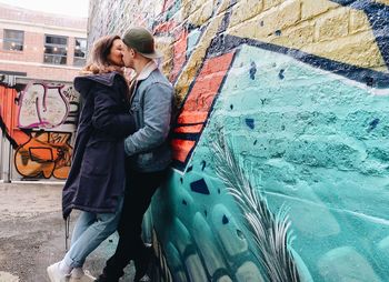 Full length of woman standing against graffiti wall