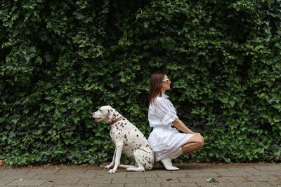 Side view of woman with dog against green wall