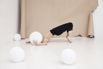 Young woman with balloon practicing yoga by brown backdrop