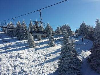 Ski lift over snow covered field against sky