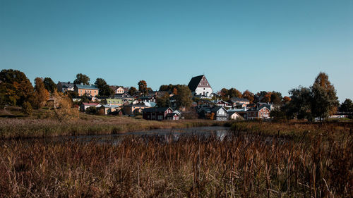 Houses on field against clear blue sky