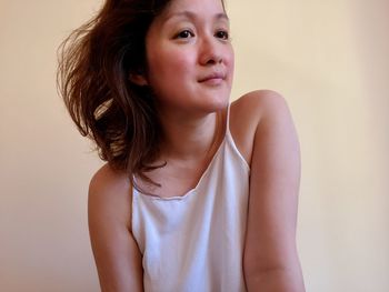 Portrait of a beautiful young woman standing against wall