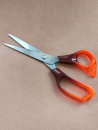 Scissors with a brown handle on the sofa
