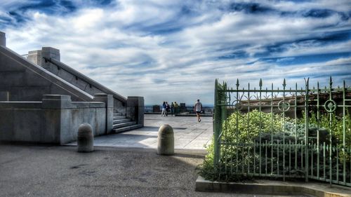 Woman walking by built structure against sky