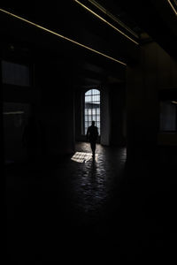 Rear view of silhouette person walking in corridor of building