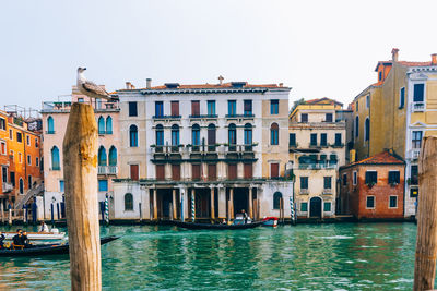 Buildings by canal against clear sky in city