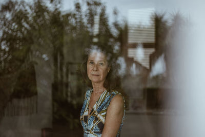 Portrait of young woman standing against a window 