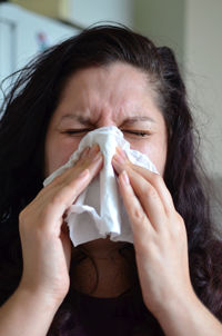 Close-up of woman sneezing at home