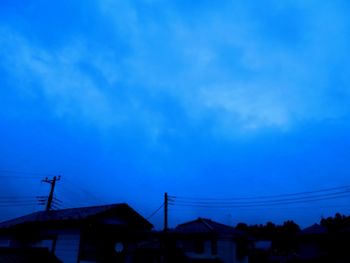 Low angle view of silhouette buildings against blue sky