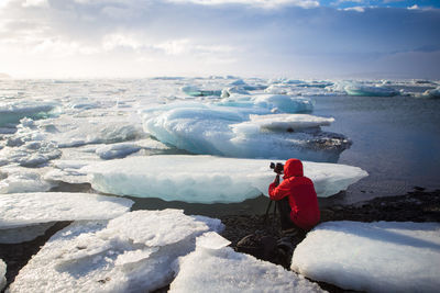 Person photographing amidst glaciers on jokulsarlon lake