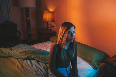 Woman sitting on bed at home