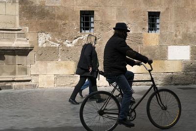 Rear view of people riding bicycle on street