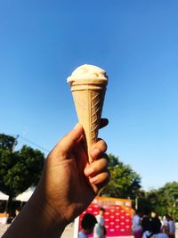 Close-up of hand holding ice cream against clear sky