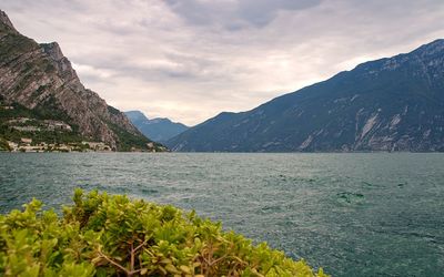 Scenic view of sea by mountains against sky