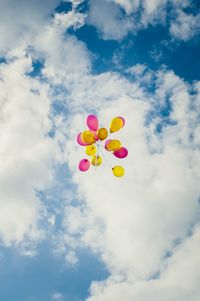 Low angle view of balloons against cloudy sky
