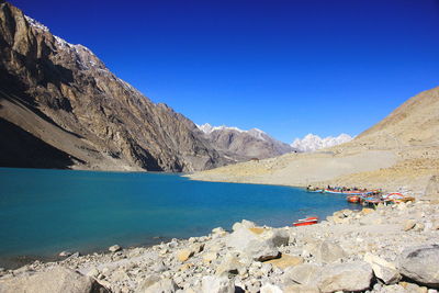 Scenic view of lake and mountains against clear blue sky