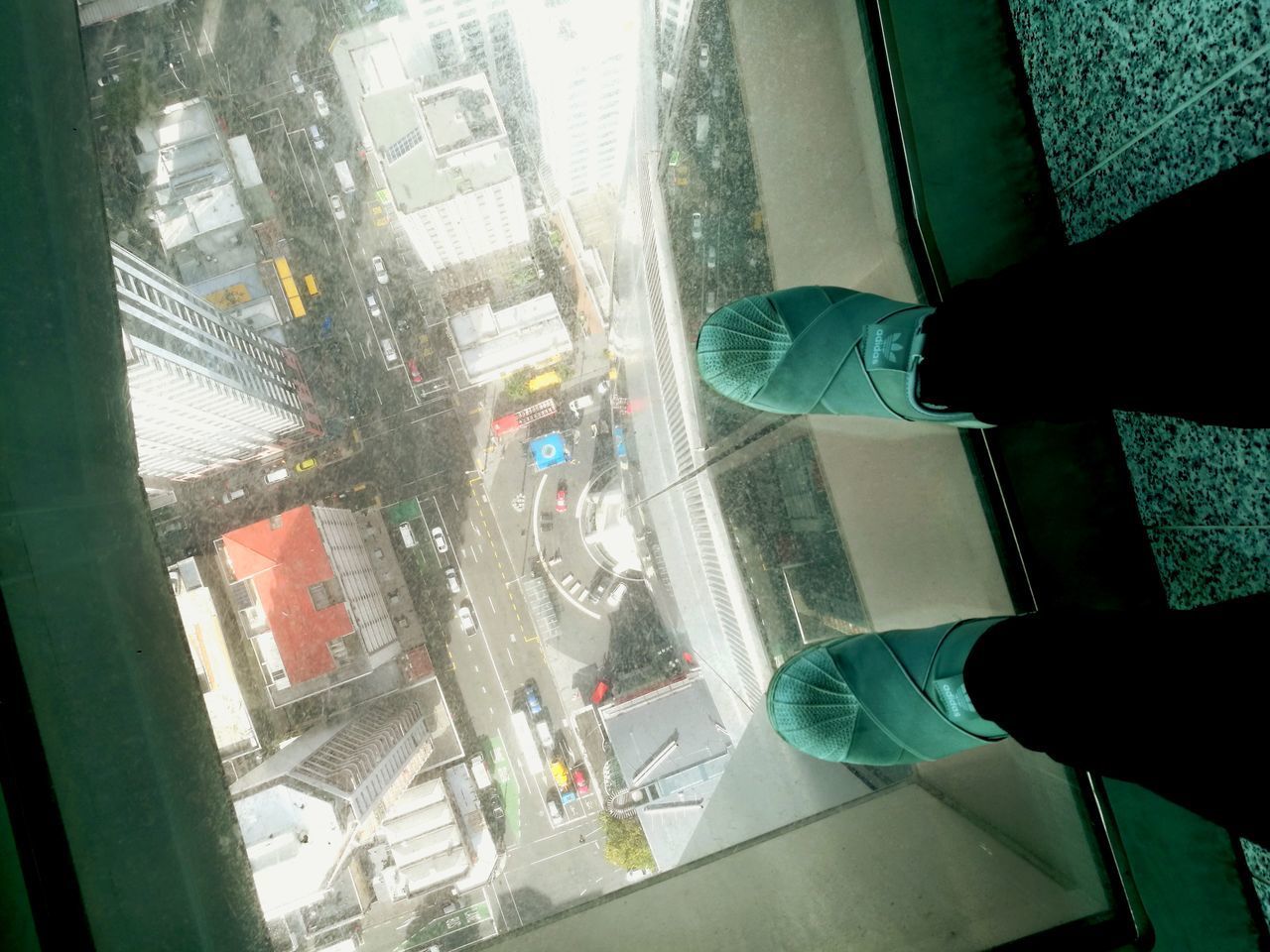 LOW SECTION OF MAN STANDING BY GLASS WINDOW IN CITY