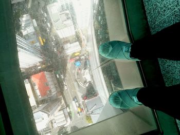 Low section of man standing by glass window