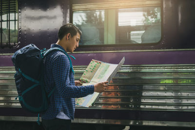 Man reading map while standing at railroad station platform