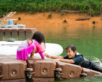 Rear view of women sitting by lake