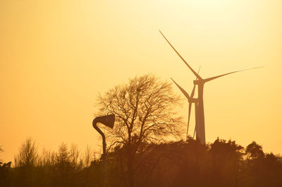 Low angle view of windmills against clear sky during sunset