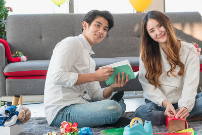 Young woman using mobile phone while sitting on sofa