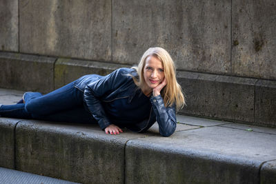 Portrait of young woman sitting against wall