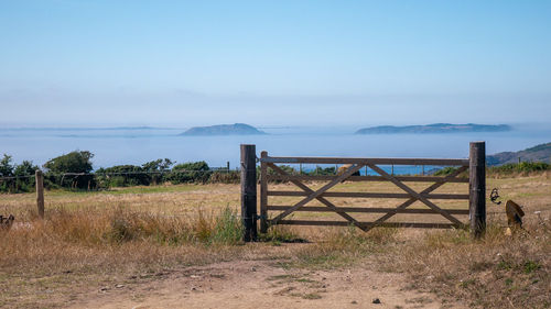 Wooden fence on field against sky