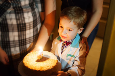 Smiling cute boy holding birthday cake at home