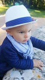 High angle view of baby girl looking away while standing by retaining wall at park