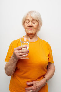 Portrait of woman holding drink against white background
