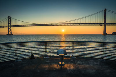 Bridge over sea against sky during sunset