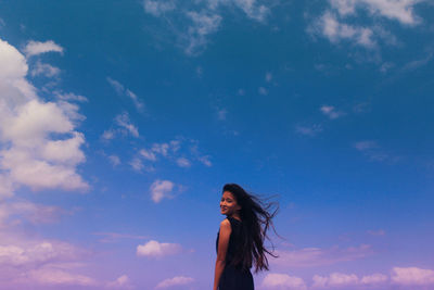 Low angle view of woman standing against blue sky