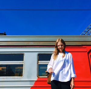 Portrait of smiling young woman standing on train